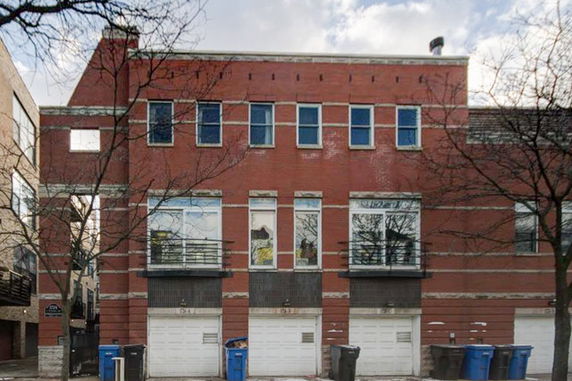 Front view of a multi-story brick building with multiple windows and garages.