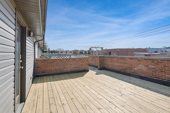 Rooftop with wooden flooring and brick wall railing.