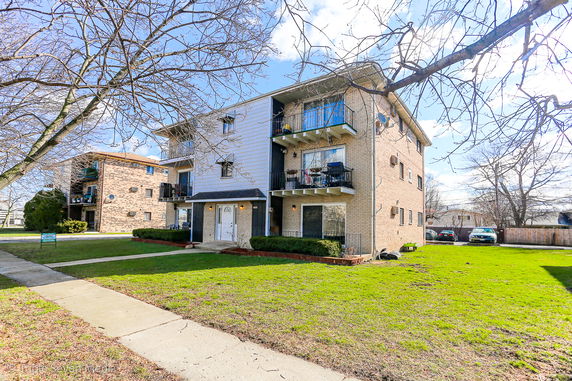 Front view of a three-story apartment building with balconies.
