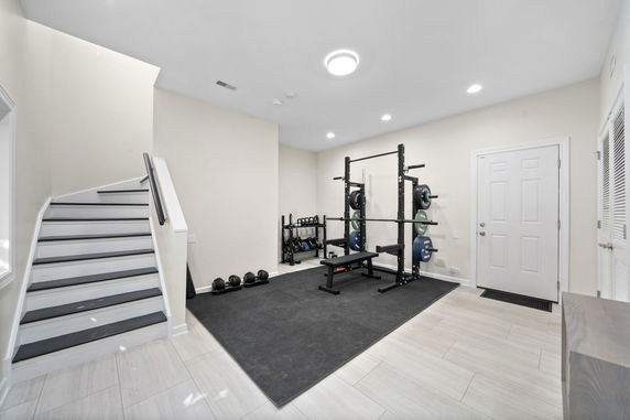 Indoor home gym area with exercise equipment and stairway.
