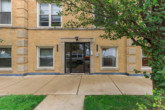 Front view of a brick building with multiple windows and a glass entrance door.