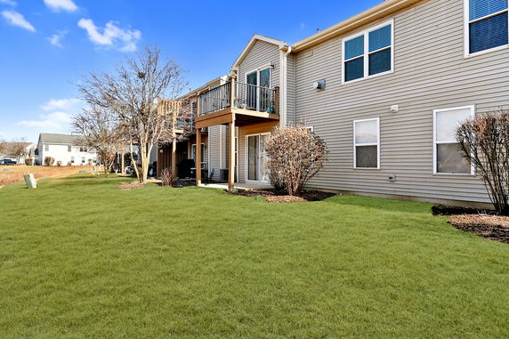 Rear view of a two-story house with a balcony and sliding doors.