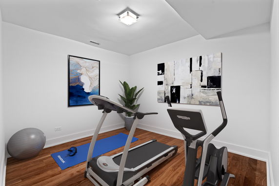 Interior view of a home gym with exercise equipment and artwork on the walls.