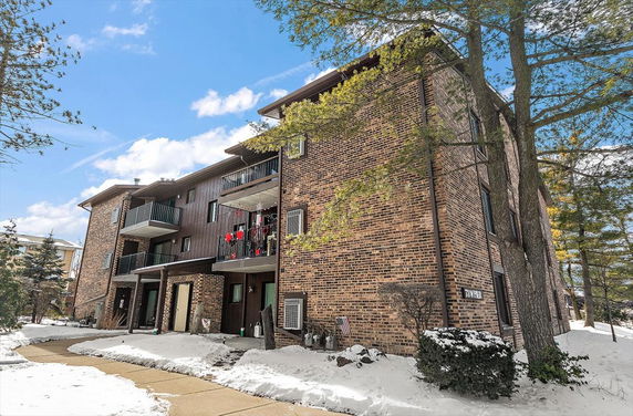 Front view of a multi-story brick apartment building with balconies.