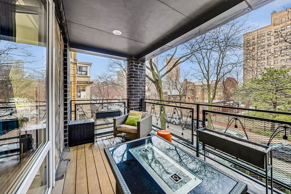 Outdoor patio with seating overlooking urban area with buildings and trees.