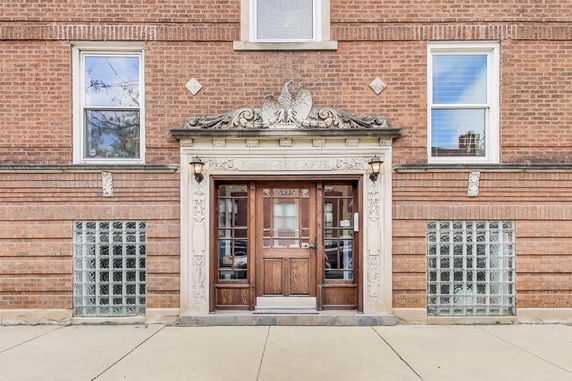Front view of a brick apartment building with decorative entrance.