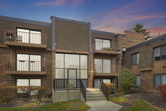 Front view of a multi-story brick apartment building with balconies.
