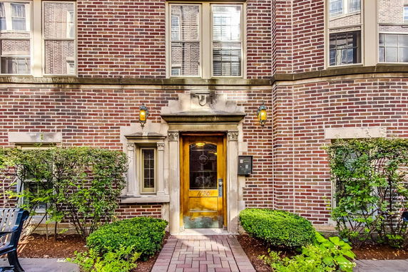 Front view of a brick building entrance with decorative stonework and lanterns.