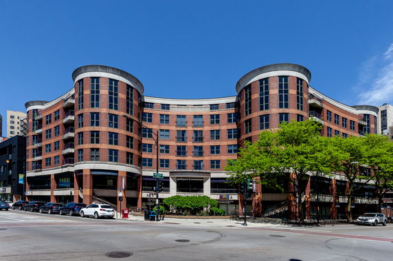 Front view of a multi-story, curved brick building with large windows.