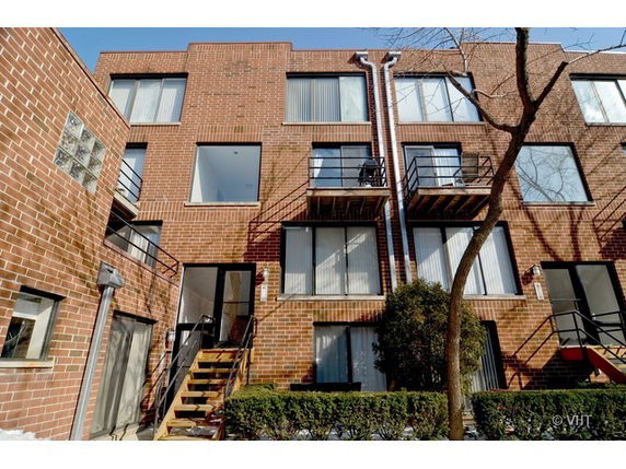 Front view of a multi-story brick apartment building with balconies.