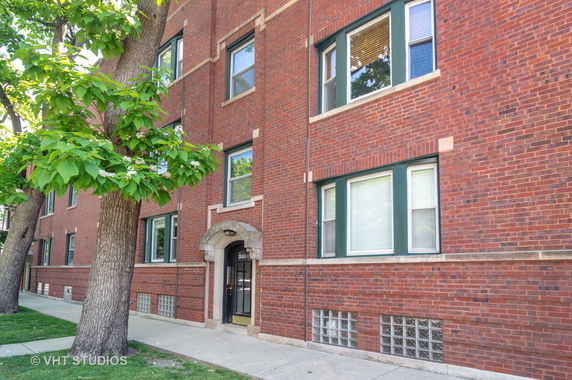 Front view of a brick apartment building with arched entrance.