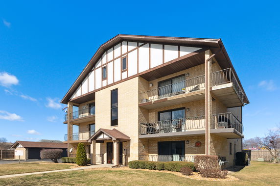 Front view of a three-story apartment building with balconies and a gable roof.