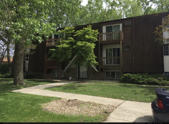Front view of a multi-story building with balconies and trees in front.