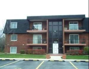 Front view of a multi-story brick apartment building with balconies.