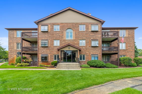 Front view of a multi-story brick apartment building with balconies.