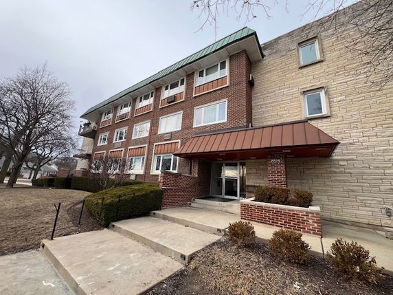 Front view of a three-story brick apartment building with an entrance canopy.