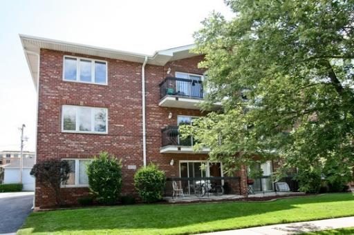 Front view of a three-story brick residential building with balconies.