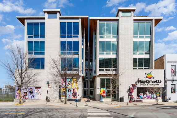 Front view of a multi-story building with large windows and a colorful retail store on the ground floor.