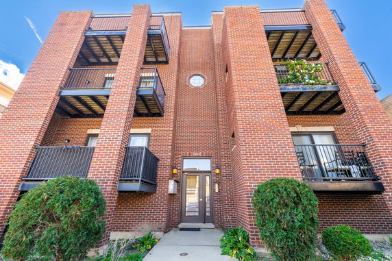 Front view of a multi-story brick apartment building with balconies.
