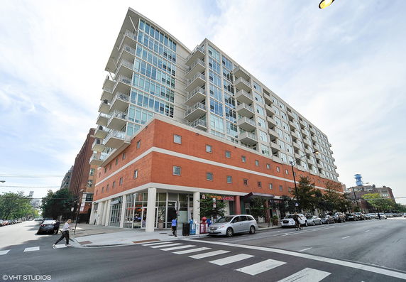 Front view of a multi-story building with balconies and a red brick facade on the lower levels.