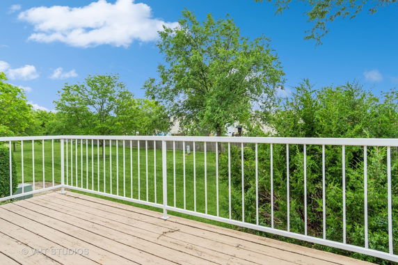 Deck with a view of green trees and grass.
