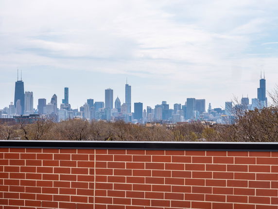 Panoramic view of a city skyline with tall buildings and a brick wall in the foreground.