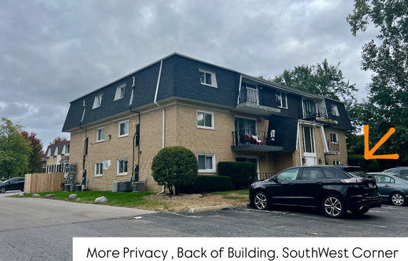 View of a three-story residential building with balconies and a mansard roof.