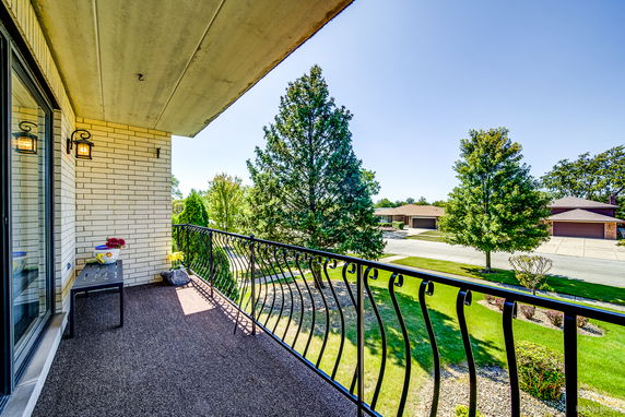 Balcony view overlooking a suburban street with trees and houses.