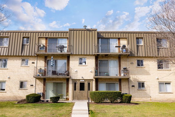 Front view of a multi-story apartment building with balconies and a central entrance.