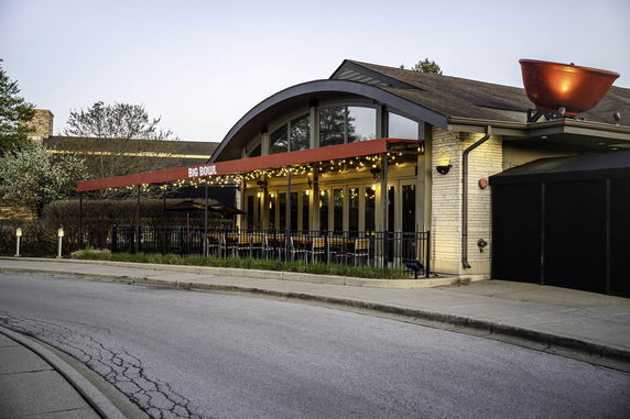 Front view of a restaurant with large windows and a patio.