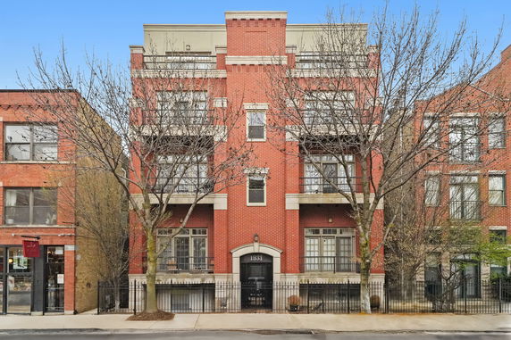 Front view of a multi-story red brick building with balconies.