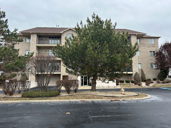Front view of a multi-story apartment building with balconies and a central entrance.