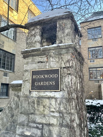 Front view of a stone structure with a plaque reading 'Rookwood Gardens'.