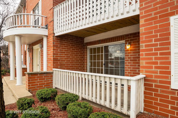 Front view of a two-story brick building with white railings and columns.