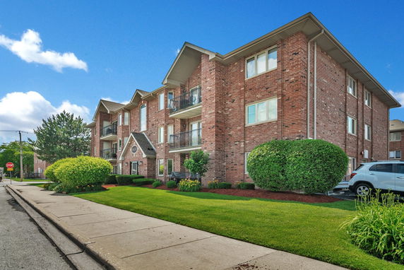 Front view of a brick three-story apartment building with balconies.