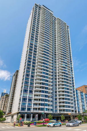 Front view of a tall modern apartment building with numerous balconies.