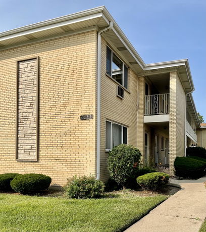 Front view of a two-story brick building with a small balcony and entrance walkway.