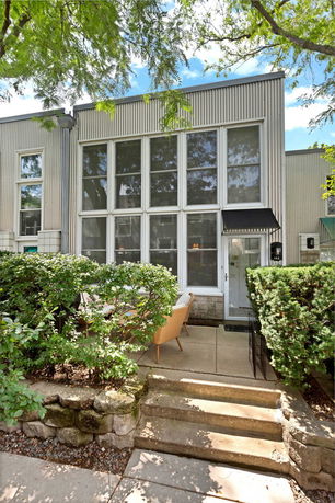 Front view of a modern house with large vertical windows and a small patio area.
