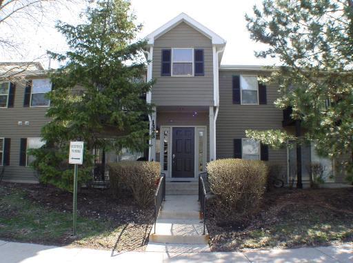 Front view of a two-story residential building with green siding and black shutters.