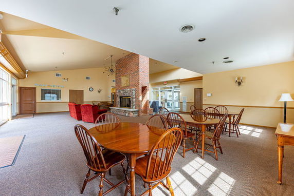 Interior view of a clubhouse with tables, chairs, and a fireplace.