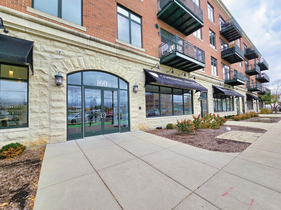 Front view of a multi-story building with balconies and large glass doors.
