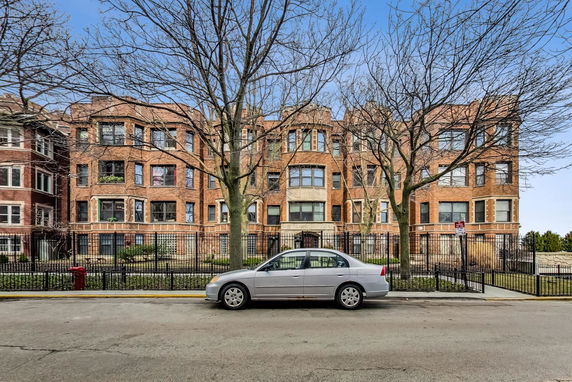 Front view of a multi-story brick building with multiple windows and a gated entrance.