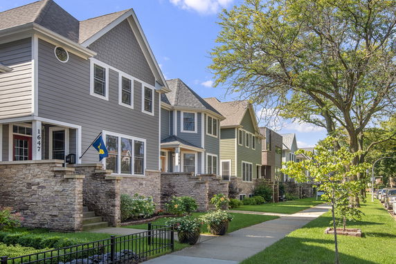 Front view of a row of two-story houses with stone and siding exteriors.