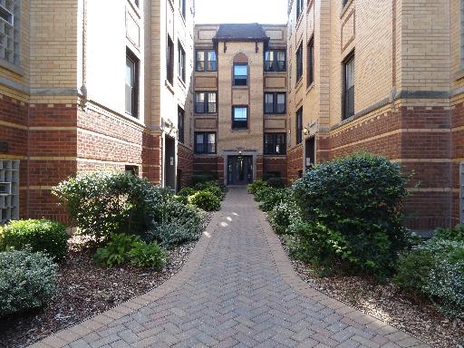 Front view of a multi-story brick building with a pathway leading to the entrance.