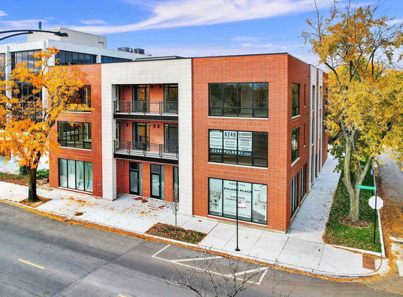 Front view of a modern three-story brick building with large windows and balconies.