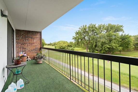 Balcony overlooking a green landscape with trees and a golf course.