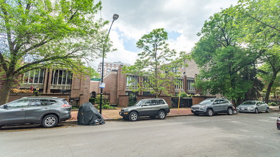 Front view of a brick building with large windows and surrounding trees.