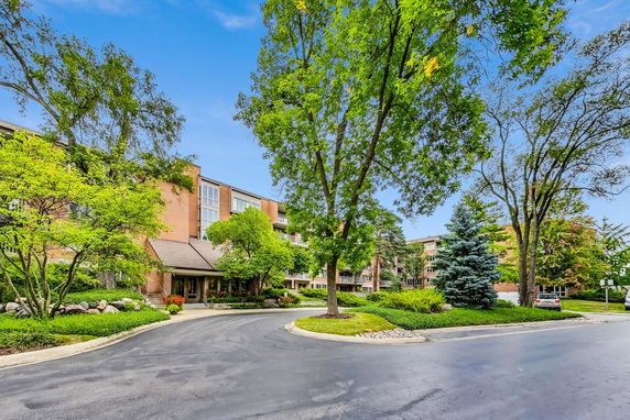 Front view of a multi-story building with a driveway and landscaped surroundings.