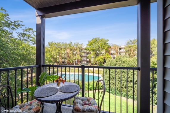 View from a balcony overlooking trees and a swimming pool.