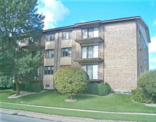 Front view of a multi-story brick apartment building with balconies.